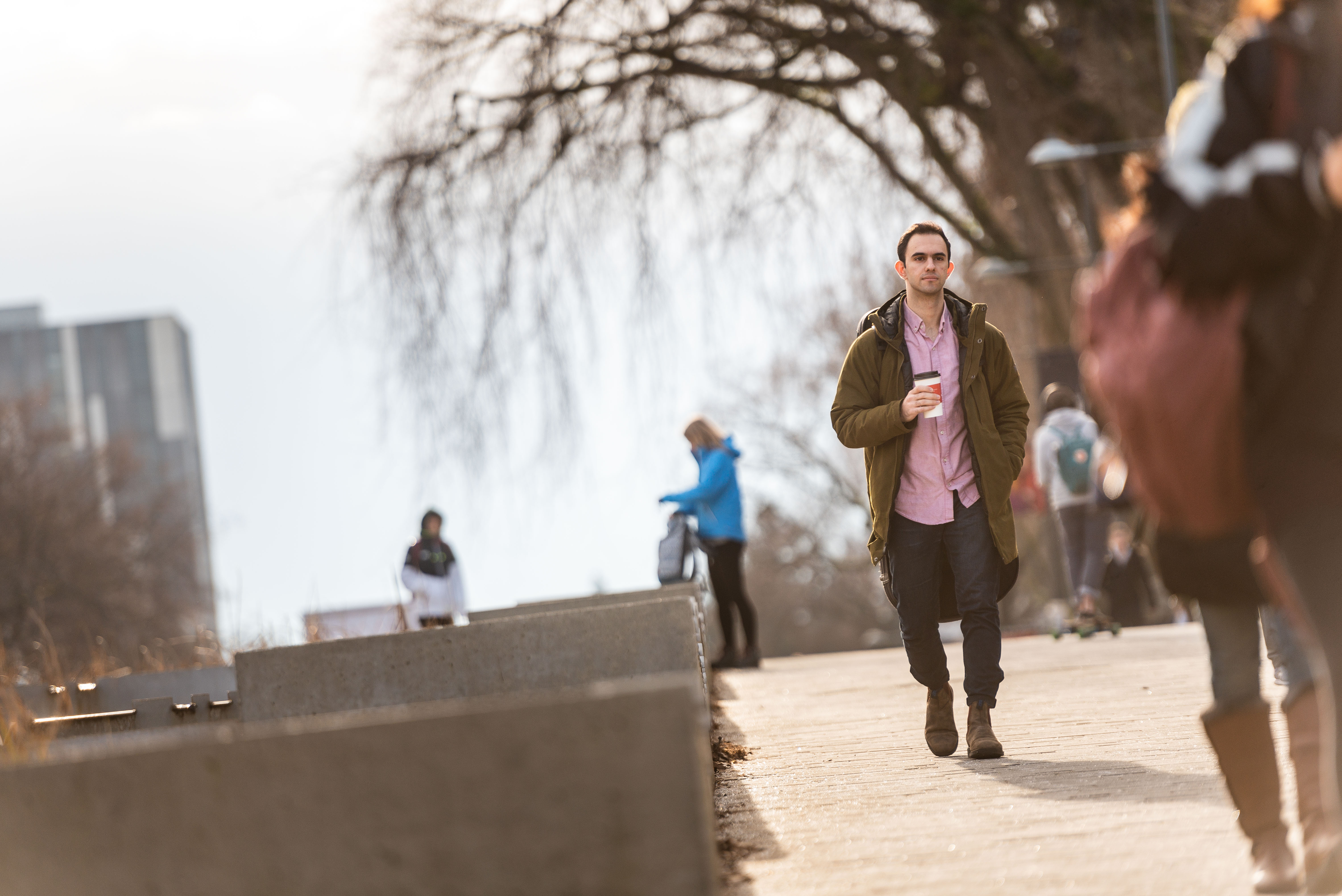 A person holding coffee walking along a path