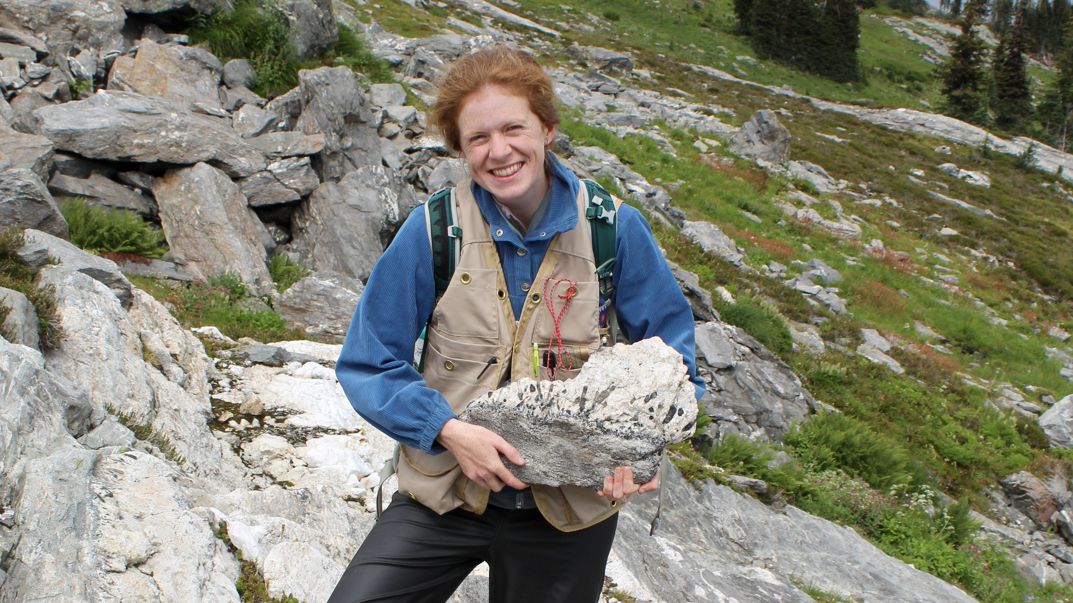 Dr. Catriona Breasley holding a pegmatite sample in the field.
