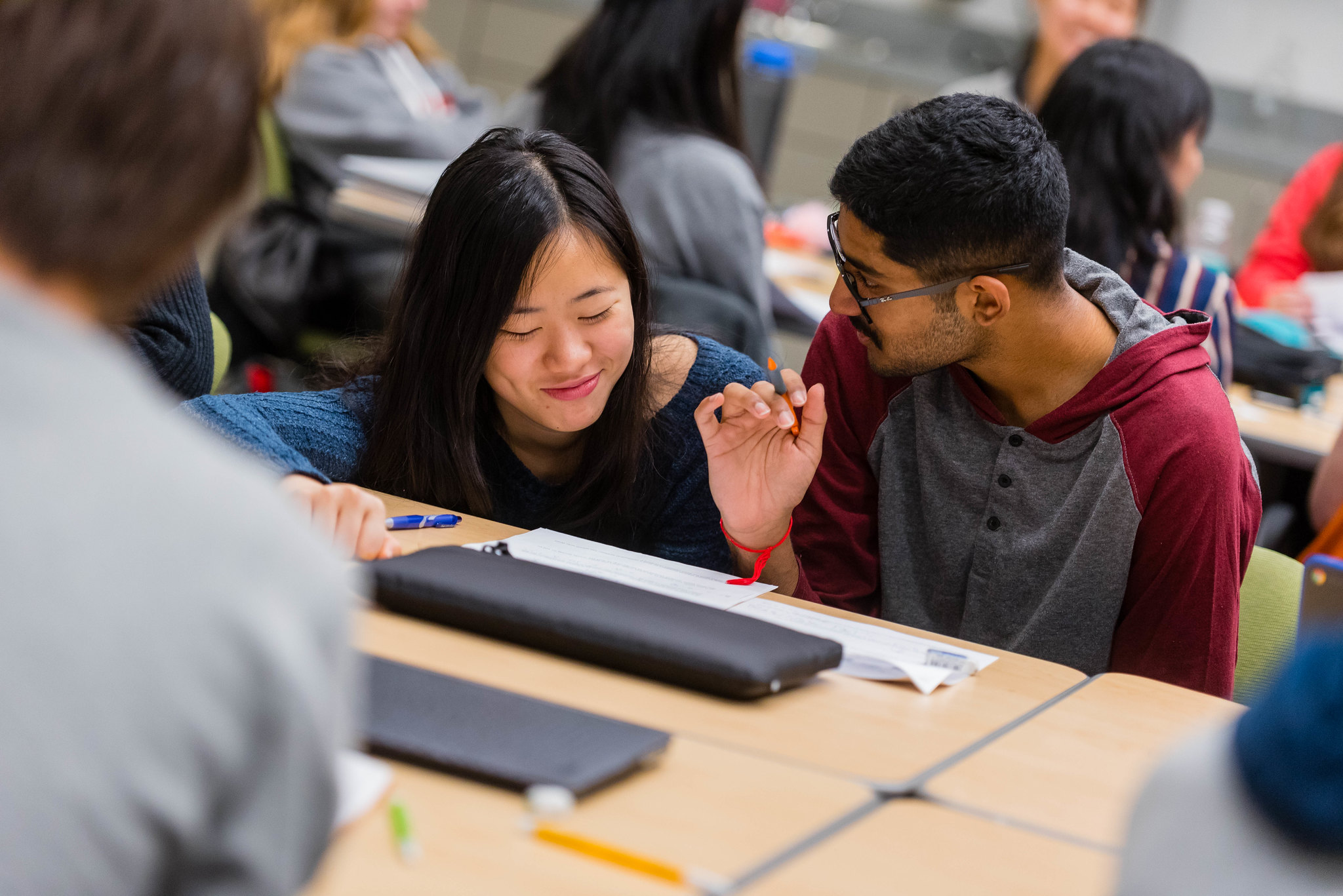 Two students are discussing homework at a desk together.