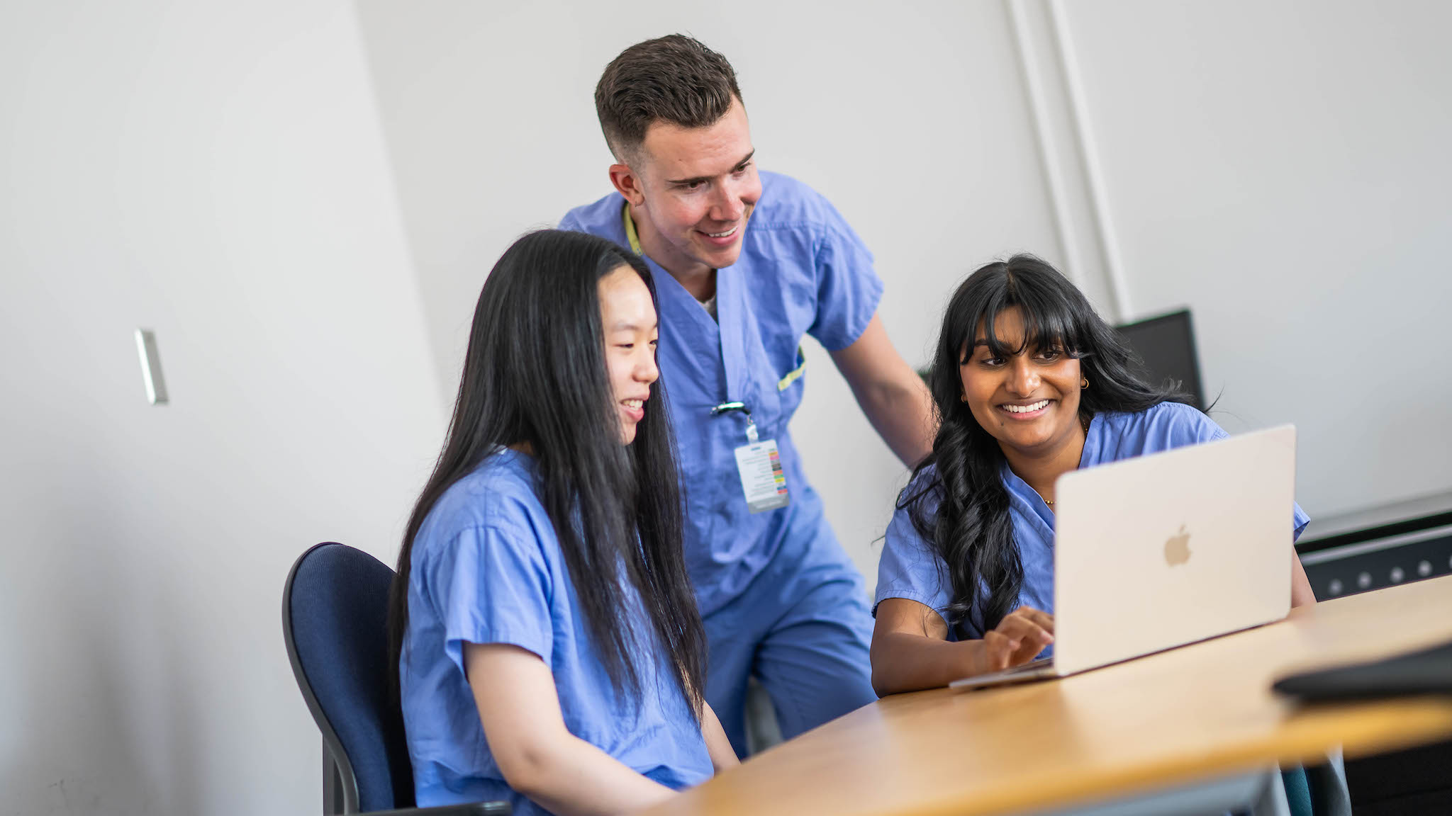 A nurse stands alongside 2 student nurses.