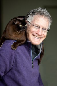 Headshot of Jonathan Losos with a black cat on his shoulder