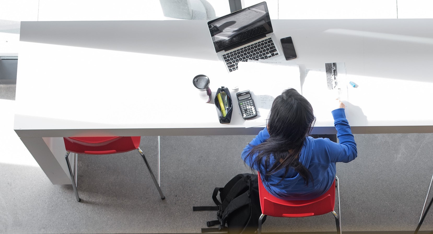 A birds-eye view of a student studying at a table with her laptop out.