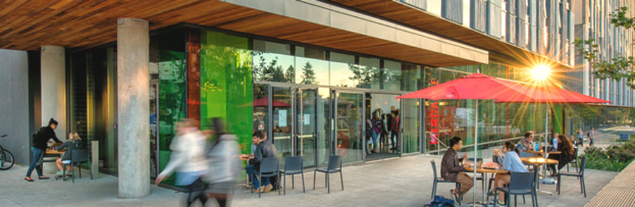 An image of an outdoor seating area with students walking by.