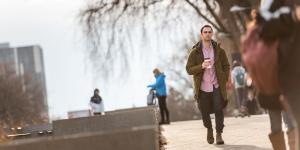 A person holding coffee walking along a path