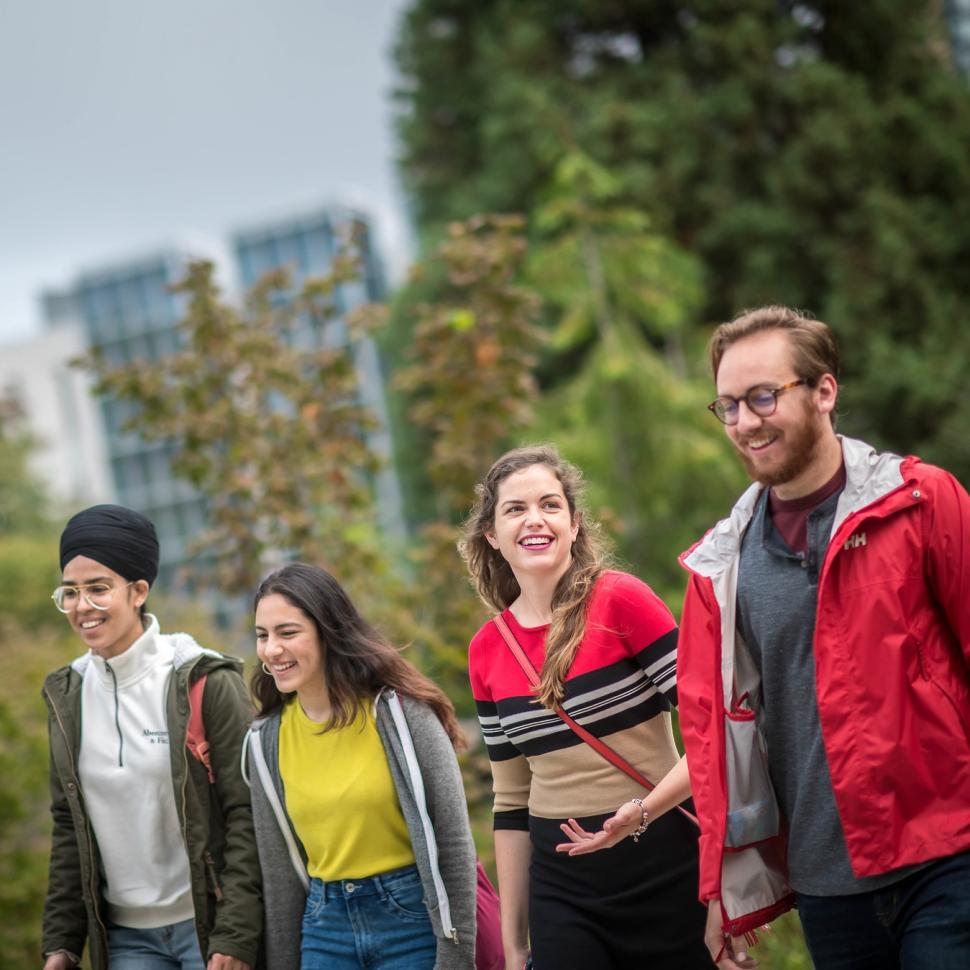 Four students walking and chatting outside on UBC campus