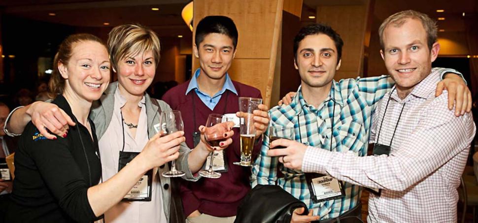5 alumni standing together holding drinks