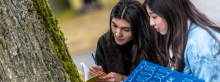 Two students taking notes about the tree in front of them