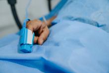 Person in a hospital bed with a pulse oximeter on their finger