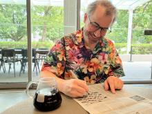 Dr. Mark MacLachlan solves a crossword puzzle in a newspaper