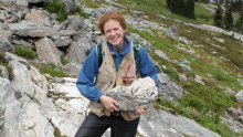 Dr. Catriona Breasley holding a pegmatite sample in the field.