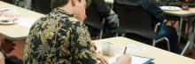 A closeup of a student sitting a table taking an exam