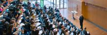 A prof giving a lecture to a full lecture hall.